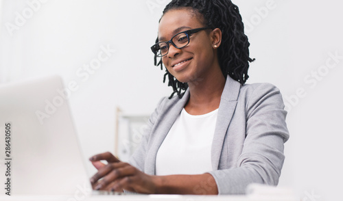 Smiling African American Business Lady Working On Laptop At Wokplace photo