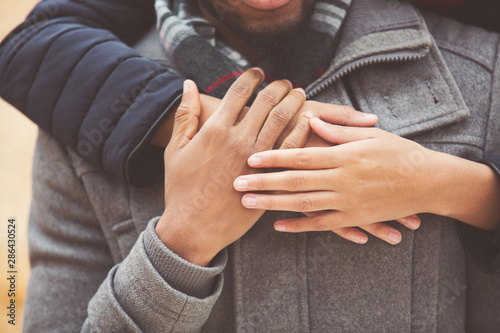 Young woman hugging man from back, closeup