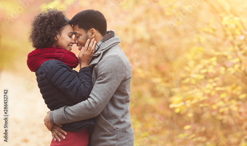 Serene afro couple hugging and touching foreheads