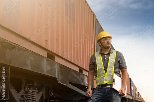Male engineer, worker inspection checking on container on the train by using computer.