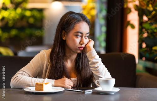 Upset young girl sitting alone at cafeteria