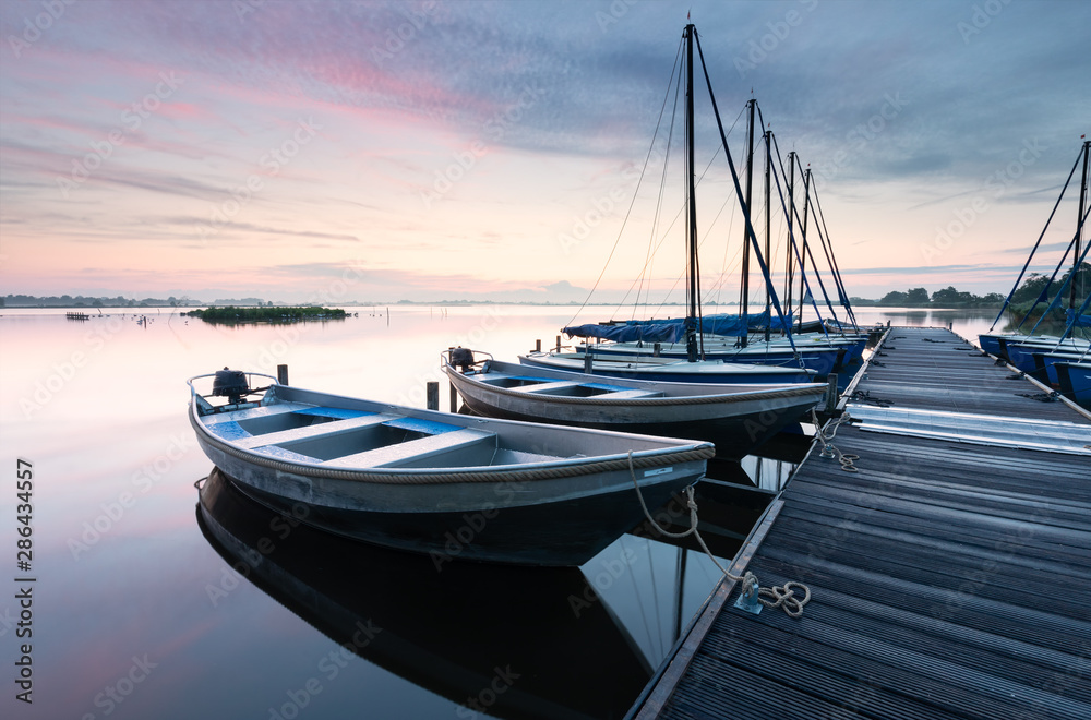 yachts by pier on big lake at dawn