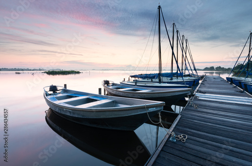 yachts by pier on big lake at dawn © Olha Rohulya