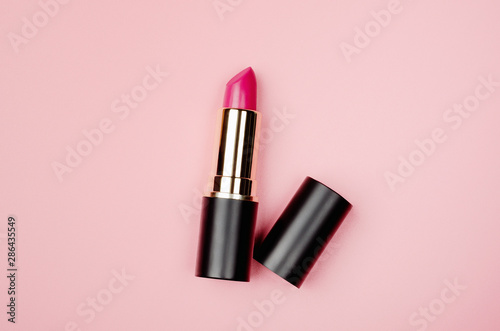 Pink lipstick tube, lip gloss top view. Beauty industry concept. Glamorous makeup accessory close up on pastel pink background. Women fashion product, style. Cosmetology, female elegance attribute photo