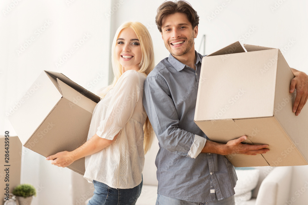 Happy Man And Woman Standing Back-To-Back Holding Moving Boxes Indoor Happy Man And Woman Standing Back-To-Back Holding Moving Boxes Indoor