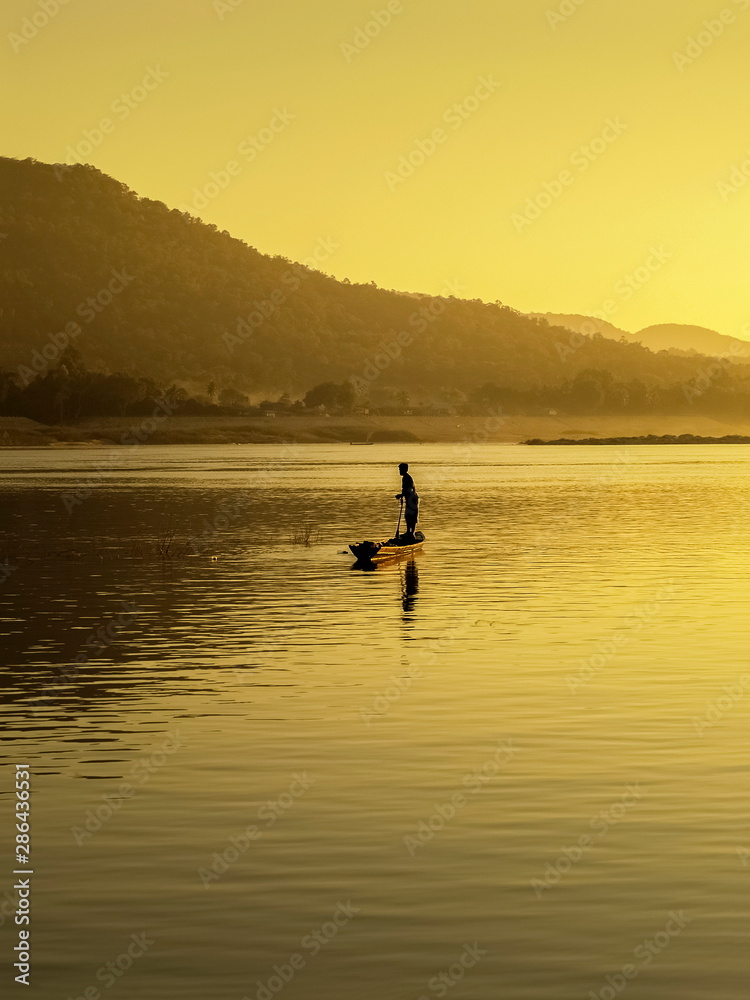 River view morning of a small fishing boat rowing in Mekong river with yellow sun light background, sunrise at Khong Chiam, Ubon Ratchathani, north-eastern of Thailand. River view morning of a small fishing boat rowing in Mekong river with yellow sun light background, sunrise at Khong Chiam, Ubon Ratchathani, north-eastern of Thailand.