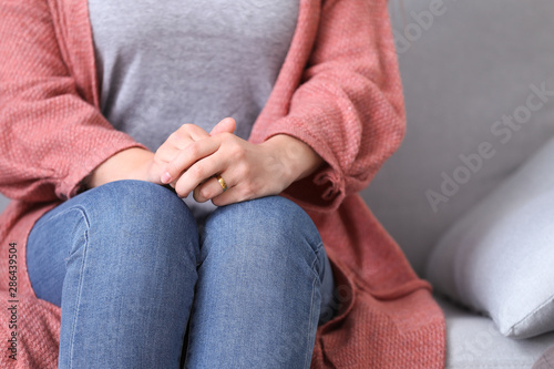 Sad woman sitting on sofa at home, closeup. Concept of divorce