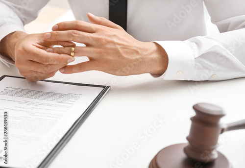 Foto Man taking wedding ring off his finger at lawyer's office