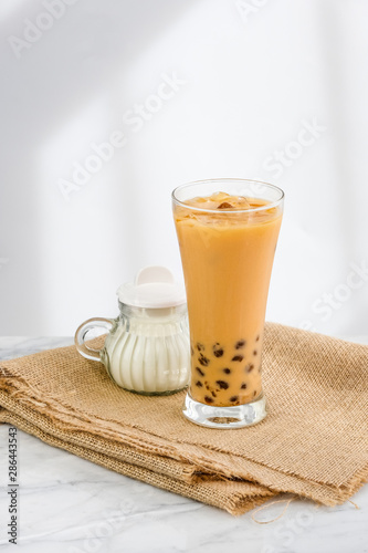 Bubble milk tea with milk and bubble topping for tea or other beverage on the wood table with copy-space for text.