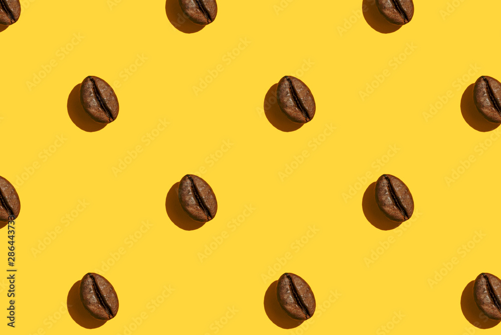 Fototapeta premium Coffee beans creative pattern on yellow background.