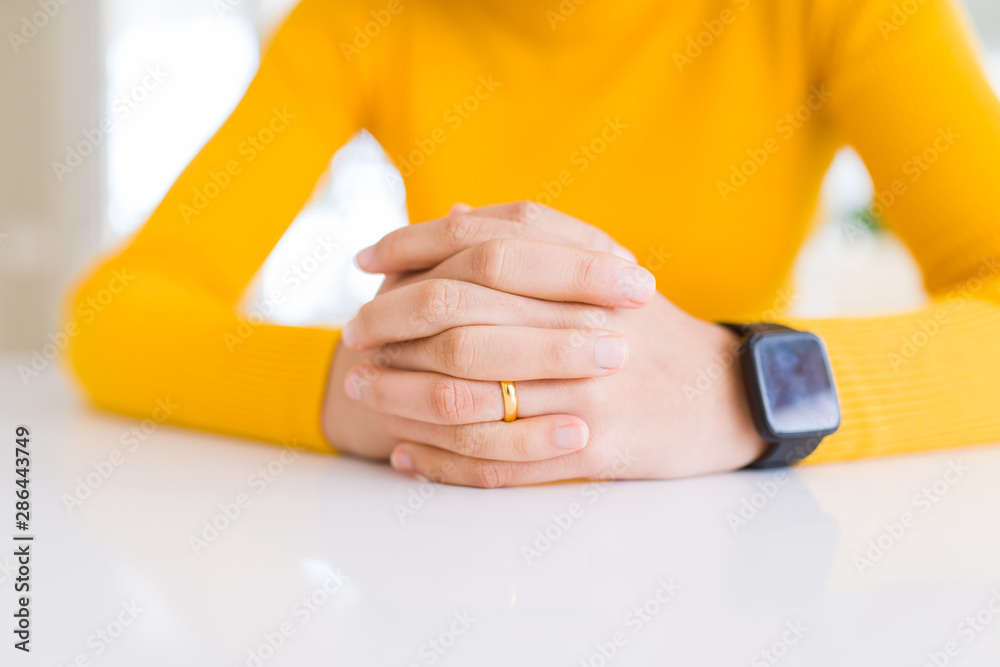 Close up of young woman hands wearing wedding alliance over white table