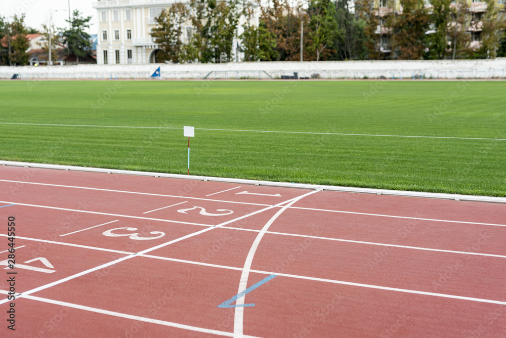 Fototapeta premium Running track with grass field on sunny day