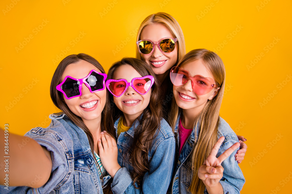 Closeup photo portrait of beautiful brunette blonde haired ladies people youth showing peace v-sign taking selfie on summer holiday isolated vivid yellow background