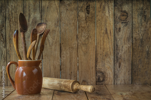 Vintage wooden utensils in the jug and rolling pin on the rustic wooden background with copy space photo