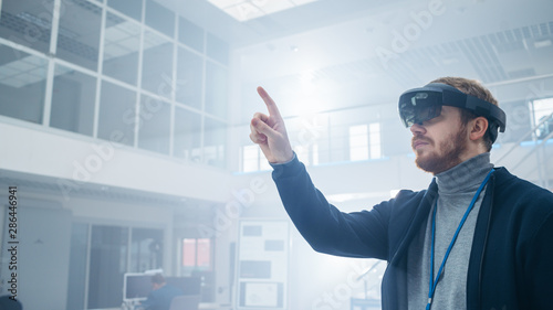 Automotive Engineer Using Augmented Reality Headset and Making Touching Gestures of Virtual Objects in the Air. In Innovation High Tech Laboratory Facility with Futuristic Atmosphere. photo