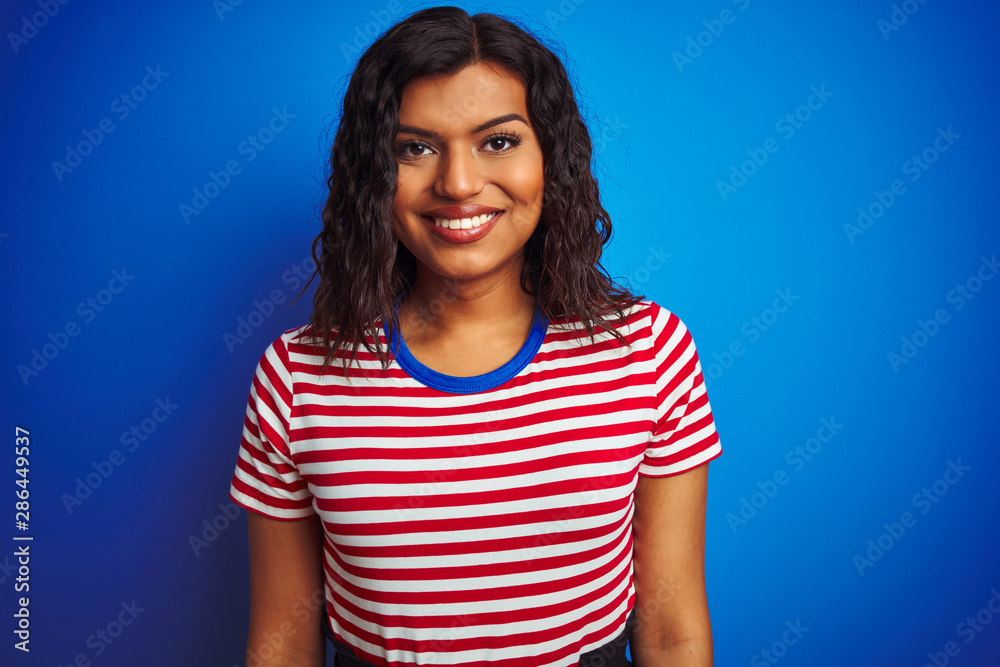 Transsexual transgender woman wearing stiped t-shirt over isolated blue background with a happy and cool smile on face. Lucky person. Transsexual transgender woman wearing stiped t-shirt over isolated blue background with a happy and cool smile on face. Lucky person.