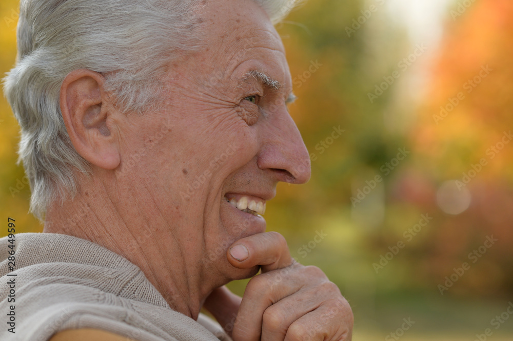 Close up portrait of happy elderly man posing in autumn park Close up portrait of happy elderly man posing in autumn park