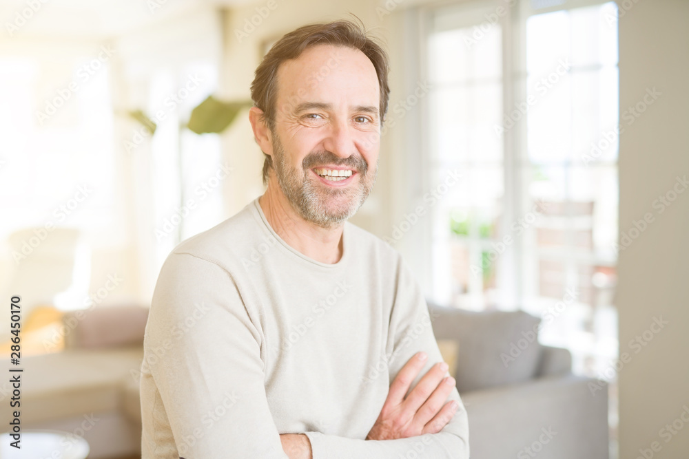 Handsome middle age man smiling looking at the camera at home Handsome middle age man smiling looking at the camera at home