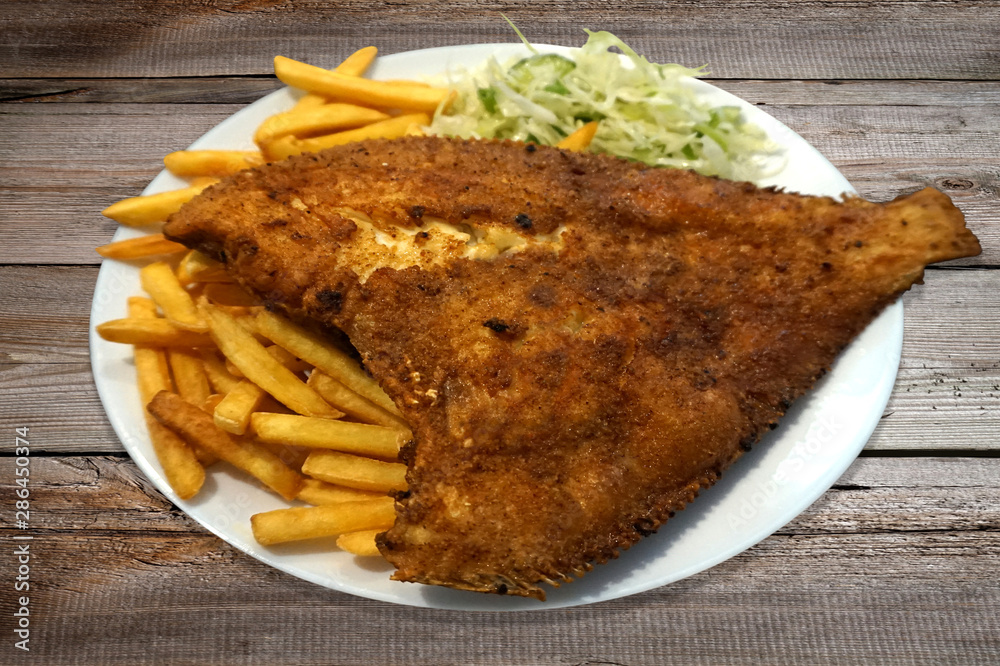 Fried fish - flounder, salad and french fries on plate Fried fish - flounder, salad and french fries on plate