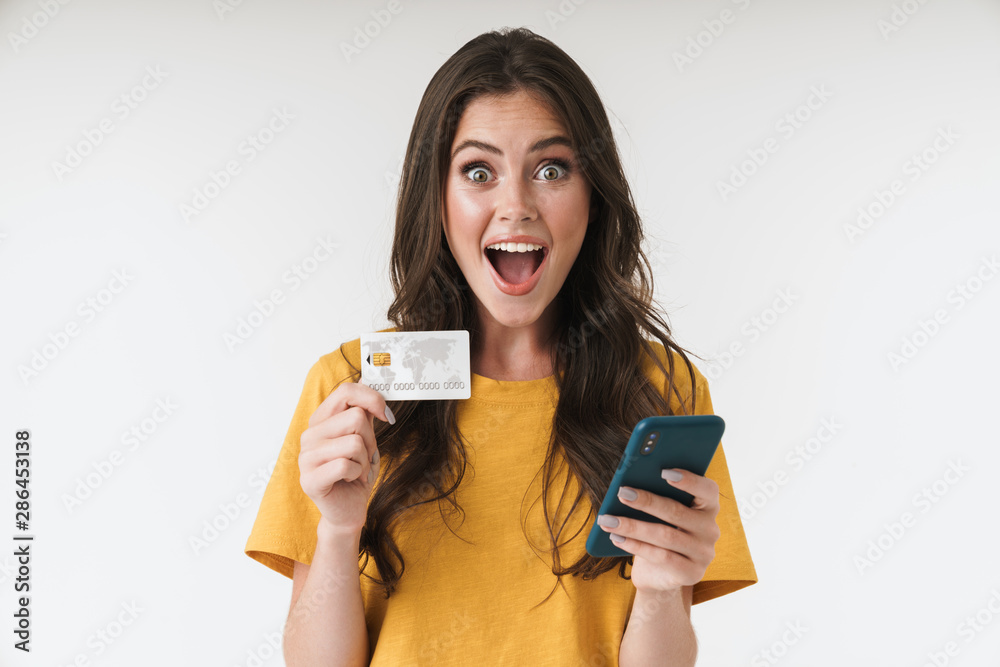 Image of beautiful brunette woman wearing casual clothes holding credit card and cellphone Image of beautiful brunette woman wearing casual clothes holding credit card and cellphone