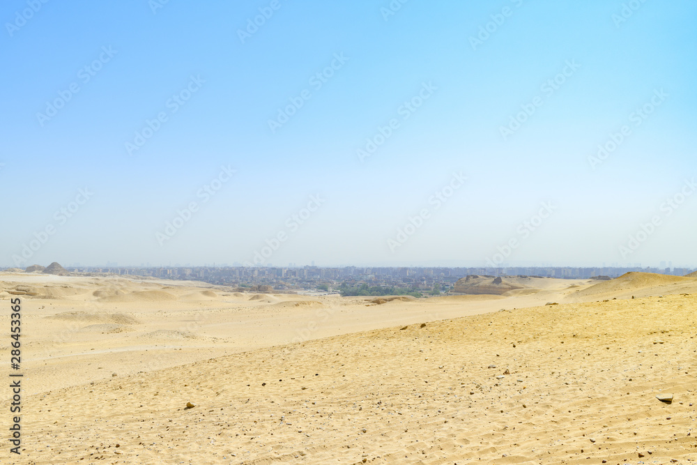 Le désert égyptien sous un ciel bleu et la ville du Caire au loin Le désert égyptien sous un ciel bleu et la ville du Caire au loin