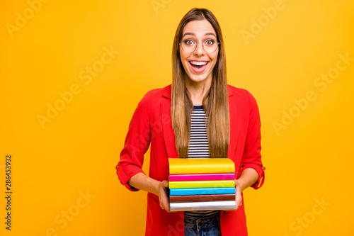 Portrait of astonished lady holding fiction books screaming wow omg wearing eyeglasses eyewear isolated over yellow background