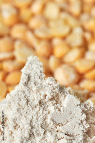 Close up picture of pea protein powder with yellow split peas in background, shallow depth of field.