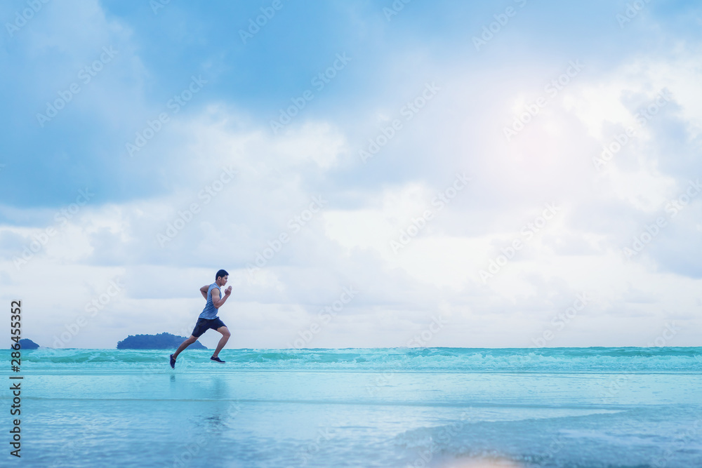 Man running athletes at the beach with sunset background.