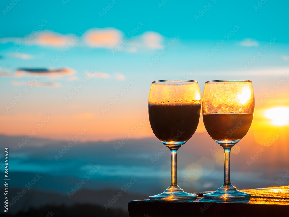 Red wine glass with the sunrise overlooking the mountains background.