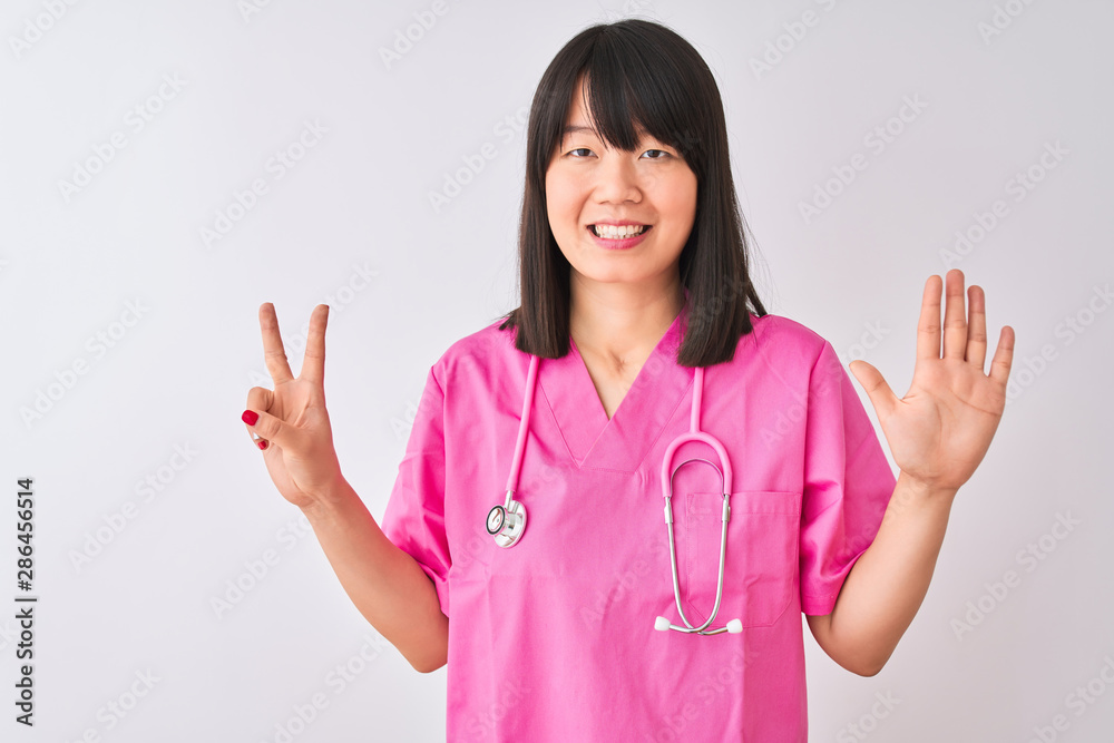 Young beautiful Chinese nurse woman wearing stethoscope over isolated white background showing and pointing up with fingers number seven while smiling confident and happy. Young beautiful Chinese nurse woman wearing stethoscope over isolated white background showing and pointing up with fingers number seven while smiling confident and happy.