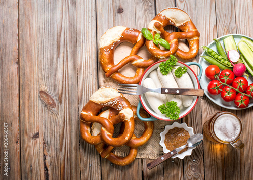 Pretzels, white bavarian sausages, beer and mustard on wooden background, german traditional food, oktoberfest