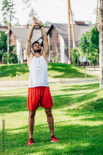 bearded athletic sportsman training on green lawn