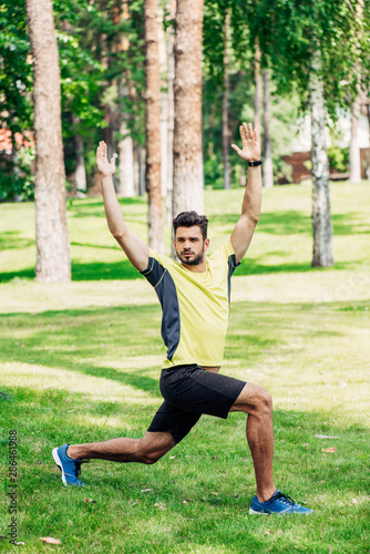 handsome bearded sportsman exercising on green lawn