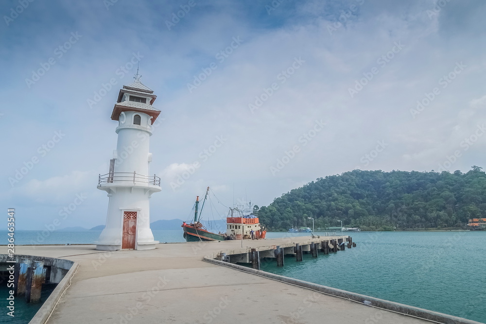 view on patch way of Lighthouse and fishing boat with cloudy sky background, Bang Bao Bay, Koh Chang, Trat Province, Thailand.