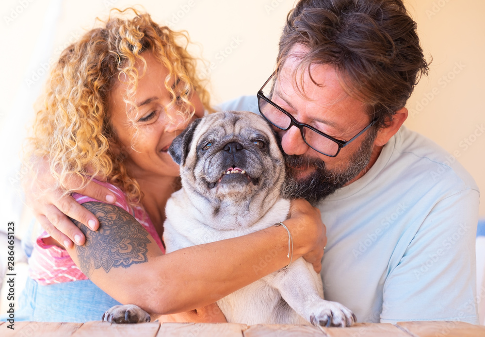 Portrait of big love between a beautiful couple of man and woman and their old pug dog. Family concept Portrait of big love between a beautiful couple of man and woman and their old pug dog. Family concept