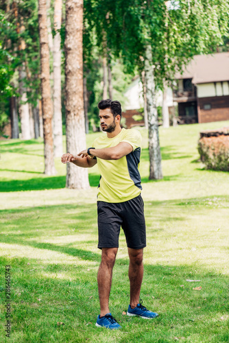 handsome young sportsman working out in park on grass
