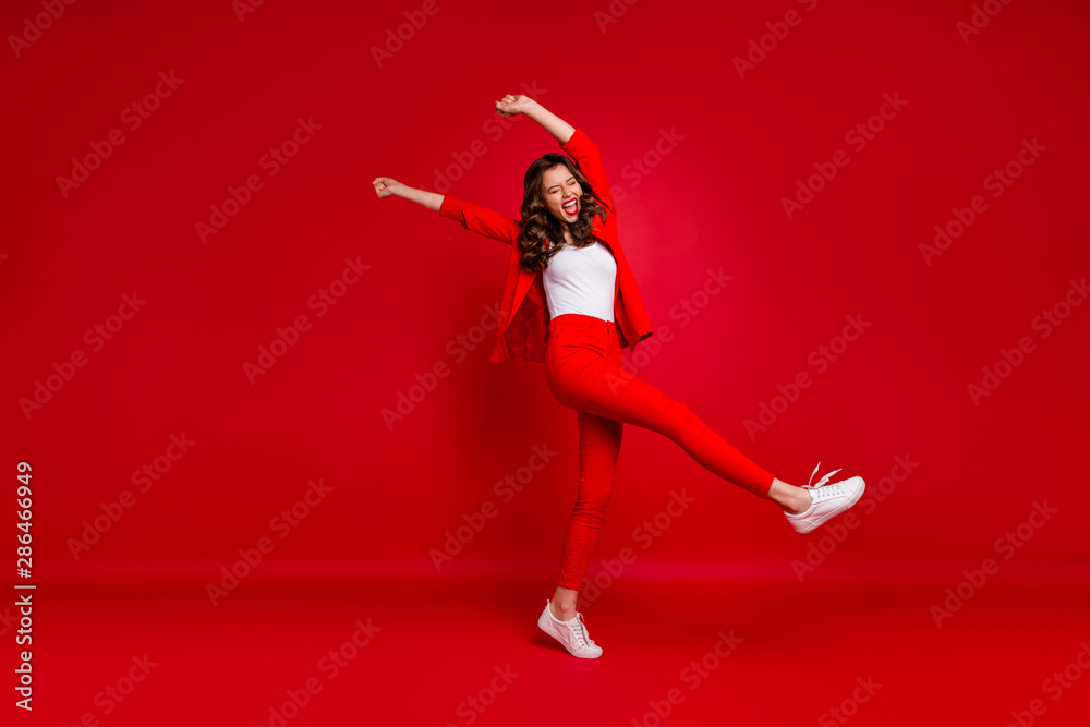 Full length photo of cheerful lady with her eyes closed screaming yeah raising fists celebrating victory isolated over red background Full length photo of cheerful lady with her eyes closed screaming yeah raising fists celebrating victory isolated over red background