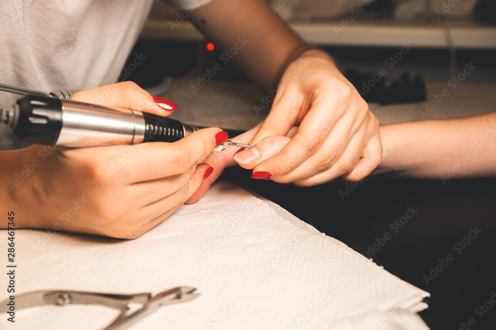 Obraz premium Woman is making a manicure. Salon procedures at home. Beautiful hands and nails.