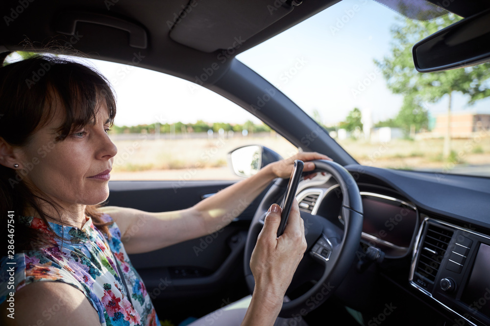 woman driving her car while using the mobile woman driving her car while using the mobile
