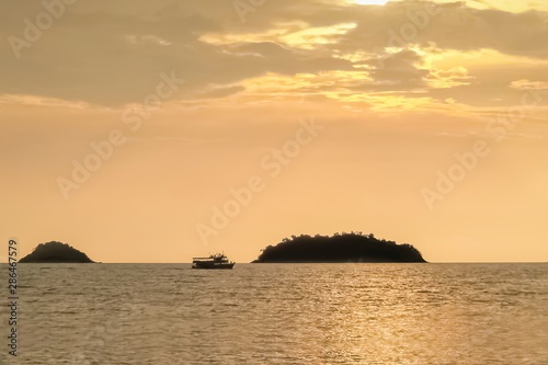 view seaside evening of a small boat floating in the sea and small island with soft sun light in the sky background, sunset at Kai Bae Beach, Koh Chang, Trat, Thailand.