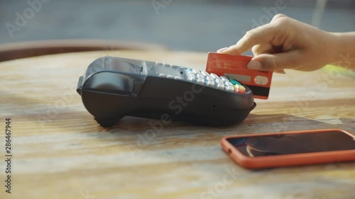 Close up hands woman paying in the cafe by credit card swiping with credit card on pos payment terminal on table in sunlight customer machine money terminal cash client electronic slow motion