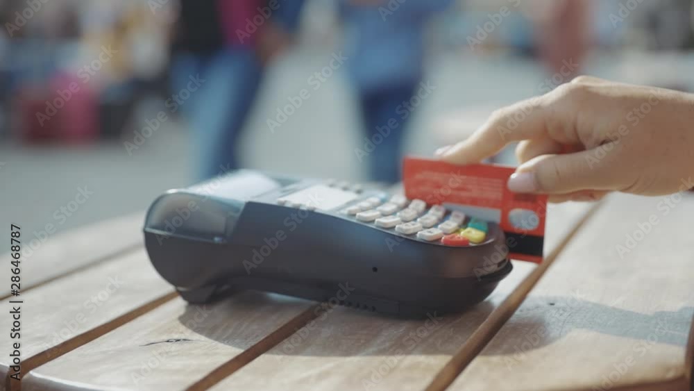 Close up hands woman paying in the cafe by credit card swiping with credit card on pos payment terminal on table in sunlight customer machine money terminal cash client electronic slow motion
