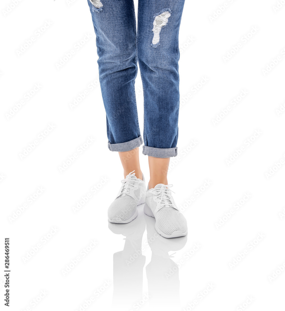 Legs in jeans and white sneakers isolated on a white background. Legs in jeans and white sneakers isolated on a white background.