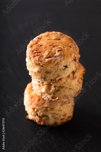 Food concept Fresh baked Homemade buttery, salty Ham and cheese scones on black background.