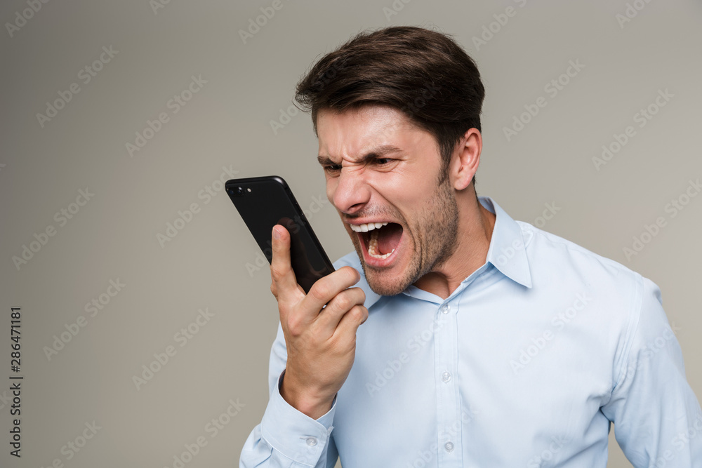 Image closeup of furious angry man wearing formal clothes shouting at cellphone Image closeup of furious angry man wearing formal clothes shouting at cellphone