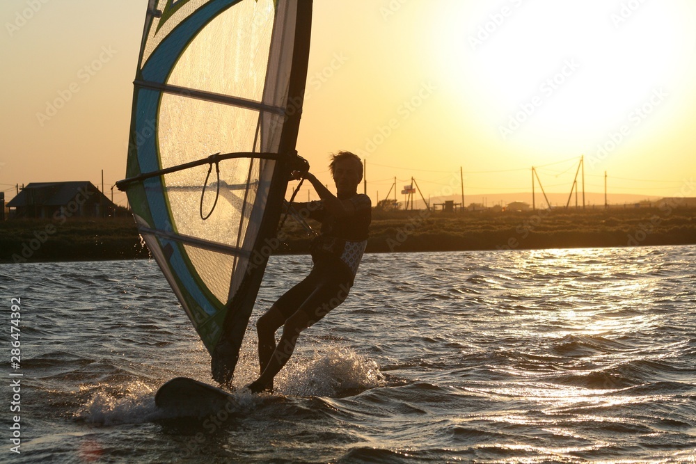Fototapeta premium Windsurfer rides at sunset in the Black sea, Russia.