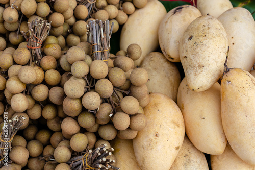 Longan and mango for sale on street market in Thailand. Tropical fruits close up photo