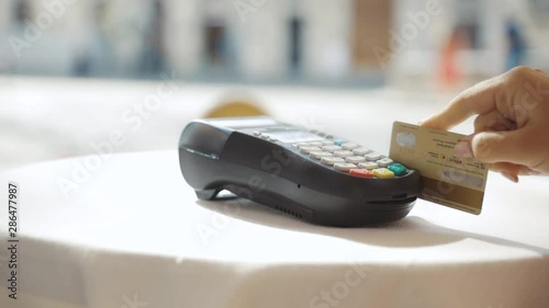 Close up hands woman paying in the cafe by credit card swiping with credit card on pos payment terminal on table in sunlight customer machine money terminal cash client electronic slow motion