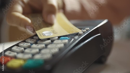 Close up hands woman paying in the cafe by credit card swiping with credit card on pos payment terminal on table in sunlight customer machine money terminal cash client electronic slow motion