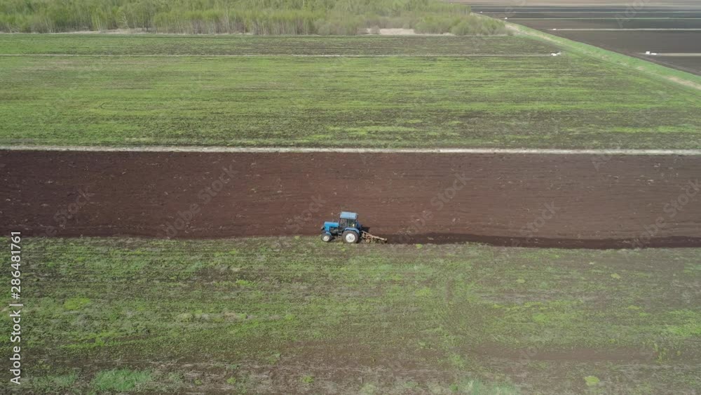 Aerial view of tractor plows the agricultural land for sowing. Plowing farming land. Aerial view of tractor plows the agricultural land for sowing. Plowing farming land.